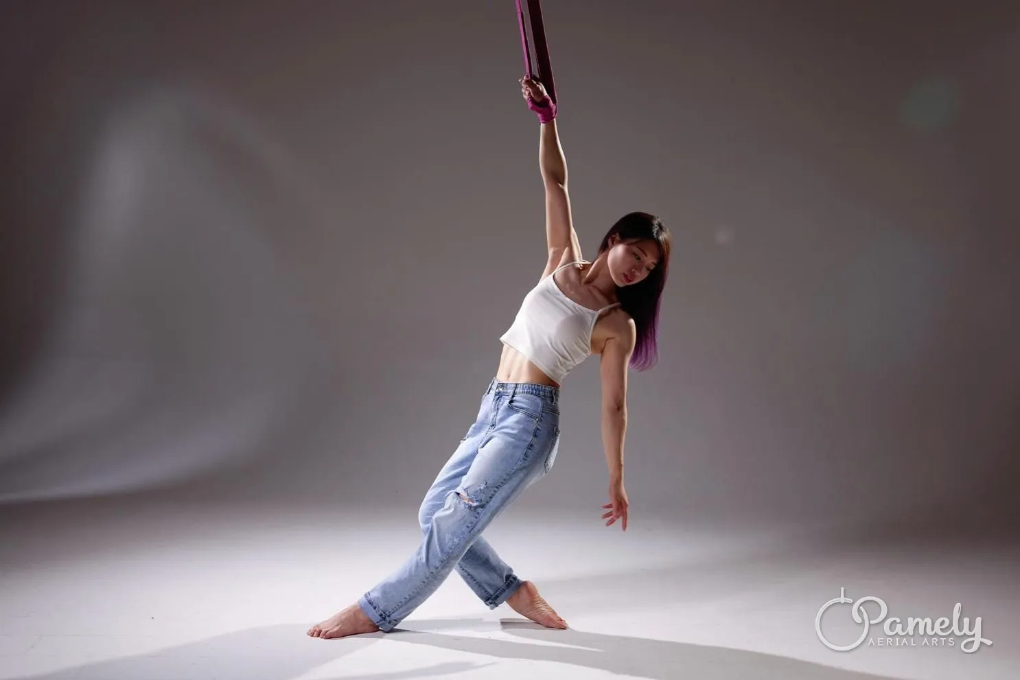 Pamely leaning from aerial straps in the studio