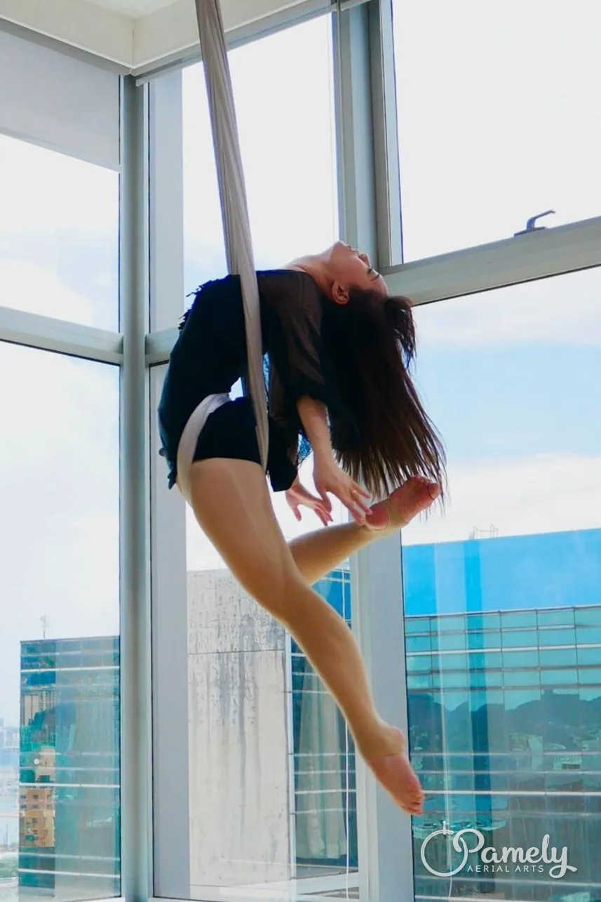 Pamely in an aerial hammock by a window