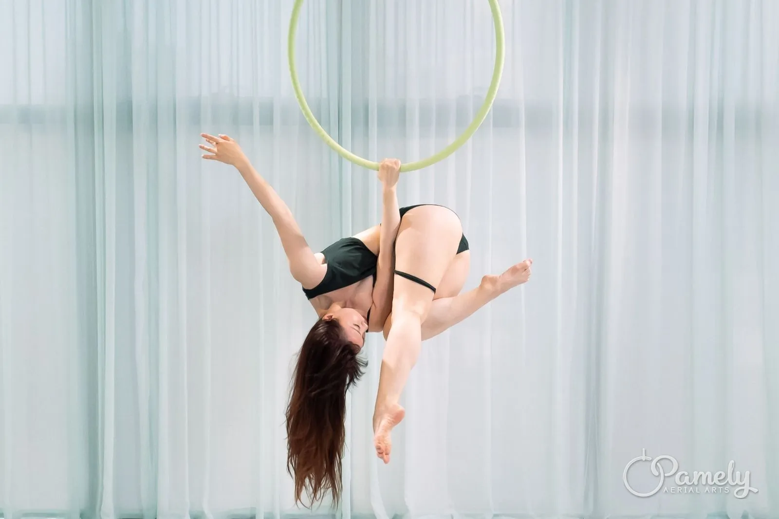 Pamely balancing on the hoop in a white studio