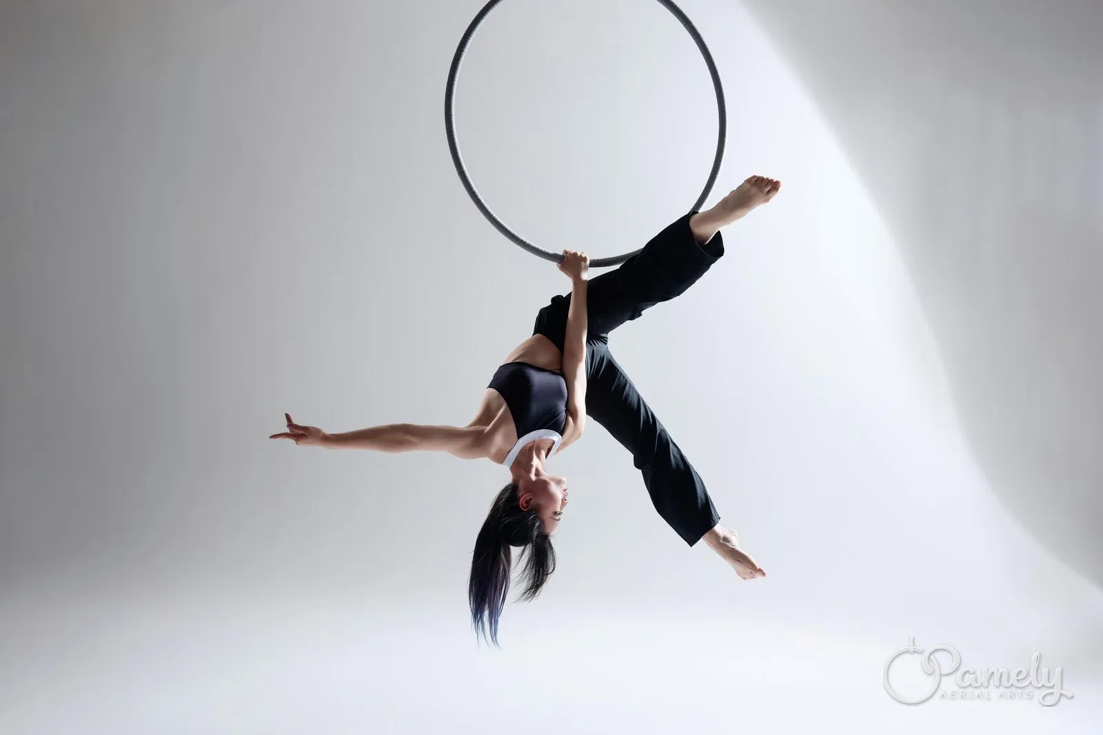 Pamely in a split beneath the hoop in a white studio