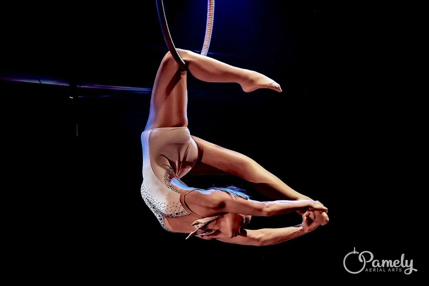 Pamely balanced in the hoop on a dark stage