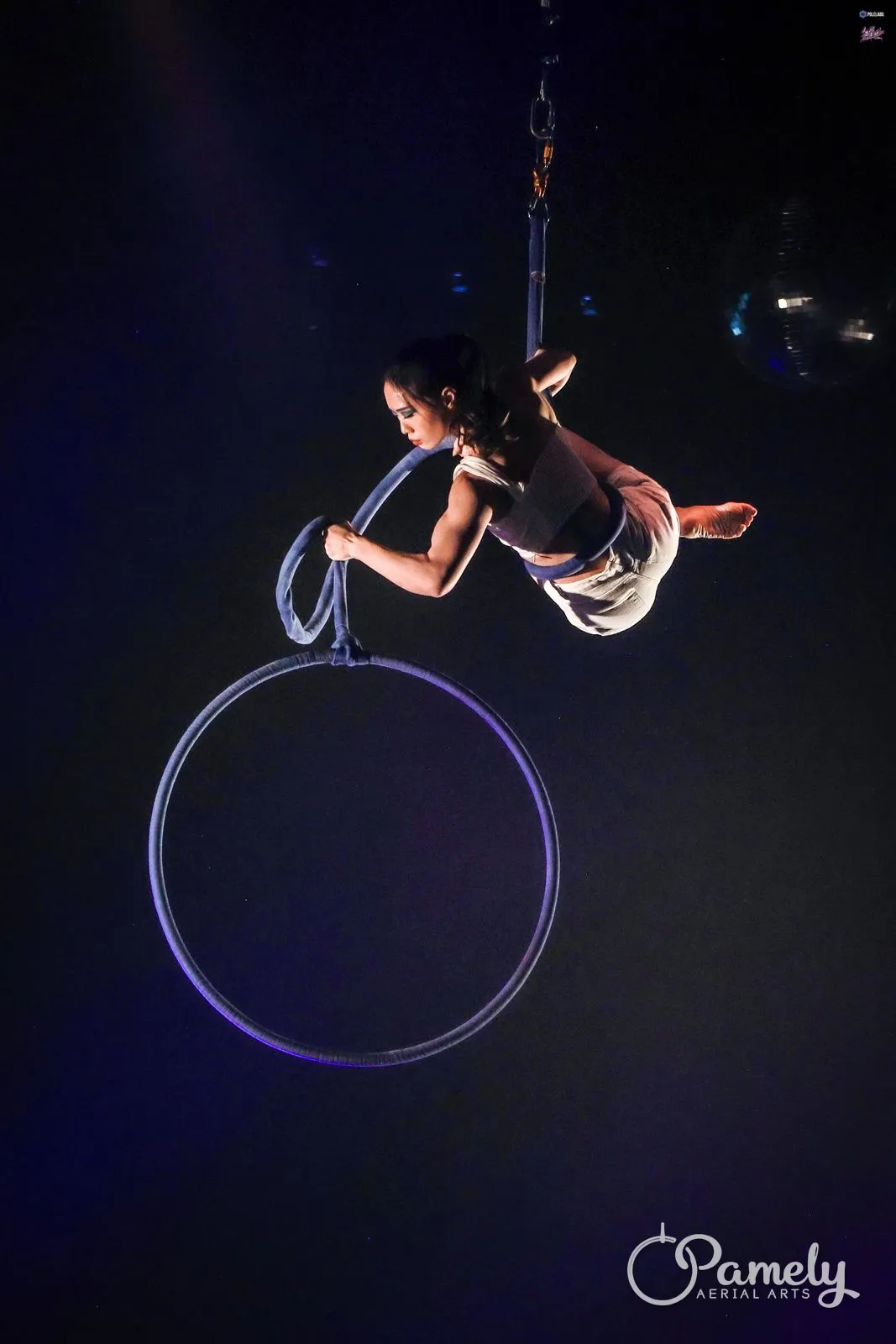 Pamely reaching out from the hoop rope under blue stage light