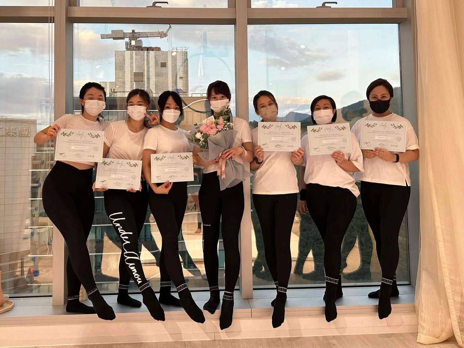 Teacher training graduates holding their certificates with Pamely
